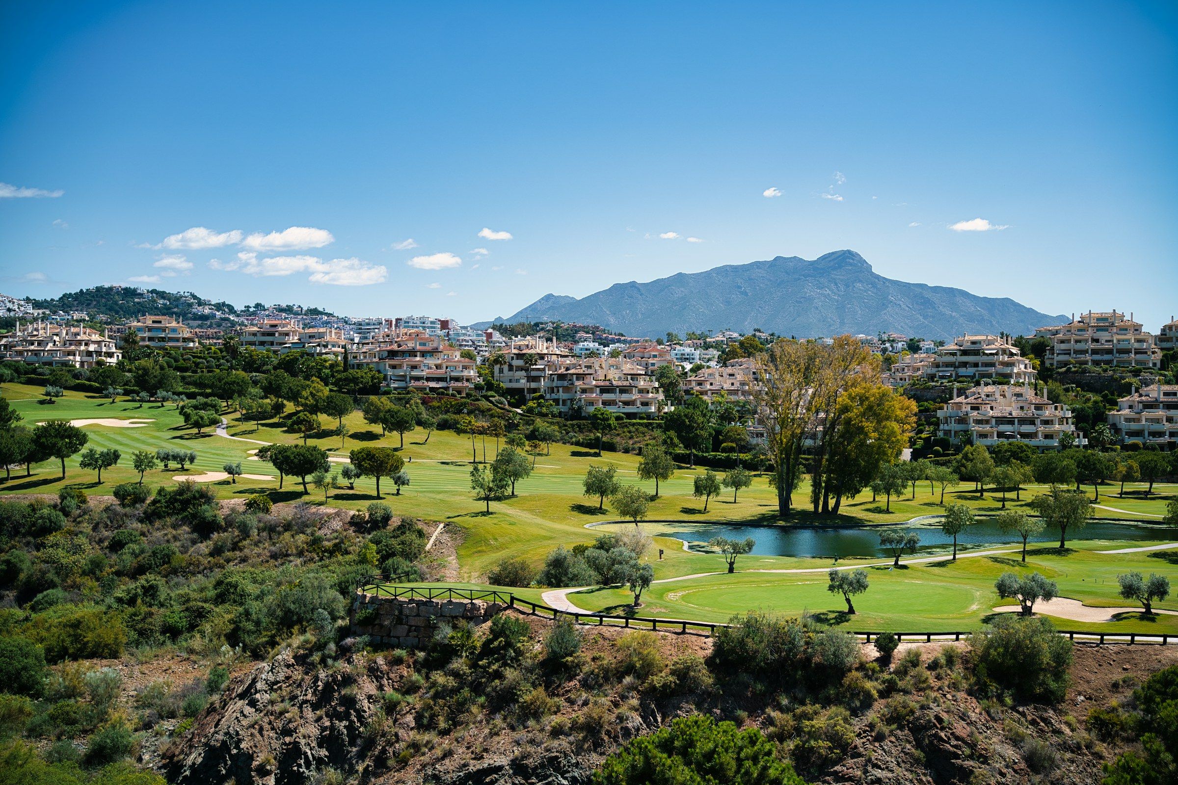 Golf Valley fairways and low-rise residences below the Sierra Blanca mountains in Nueva Andalucia, Marbella
