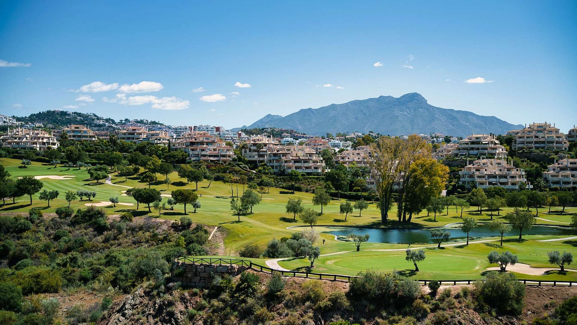 Golf Valley fairways and low-rise residences below the Sierra Blanca mountains in Nueva Andalucia, Marbella