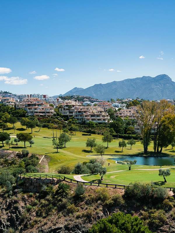 Golf Valley fairways and low-rise residences below the Sierra Blanca mountains in Nueva Andalucia, Marbella