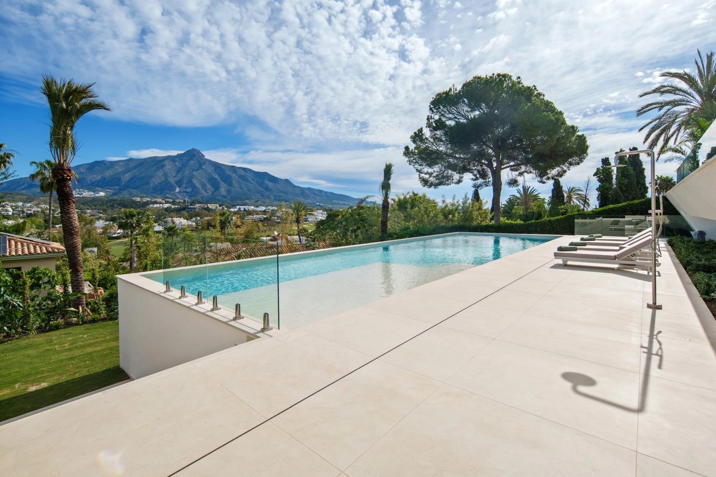 Daytime terrace and pool at Alcalá 70 in Nueva Andalucía, Marbella, with mountain and golf landscape beyond