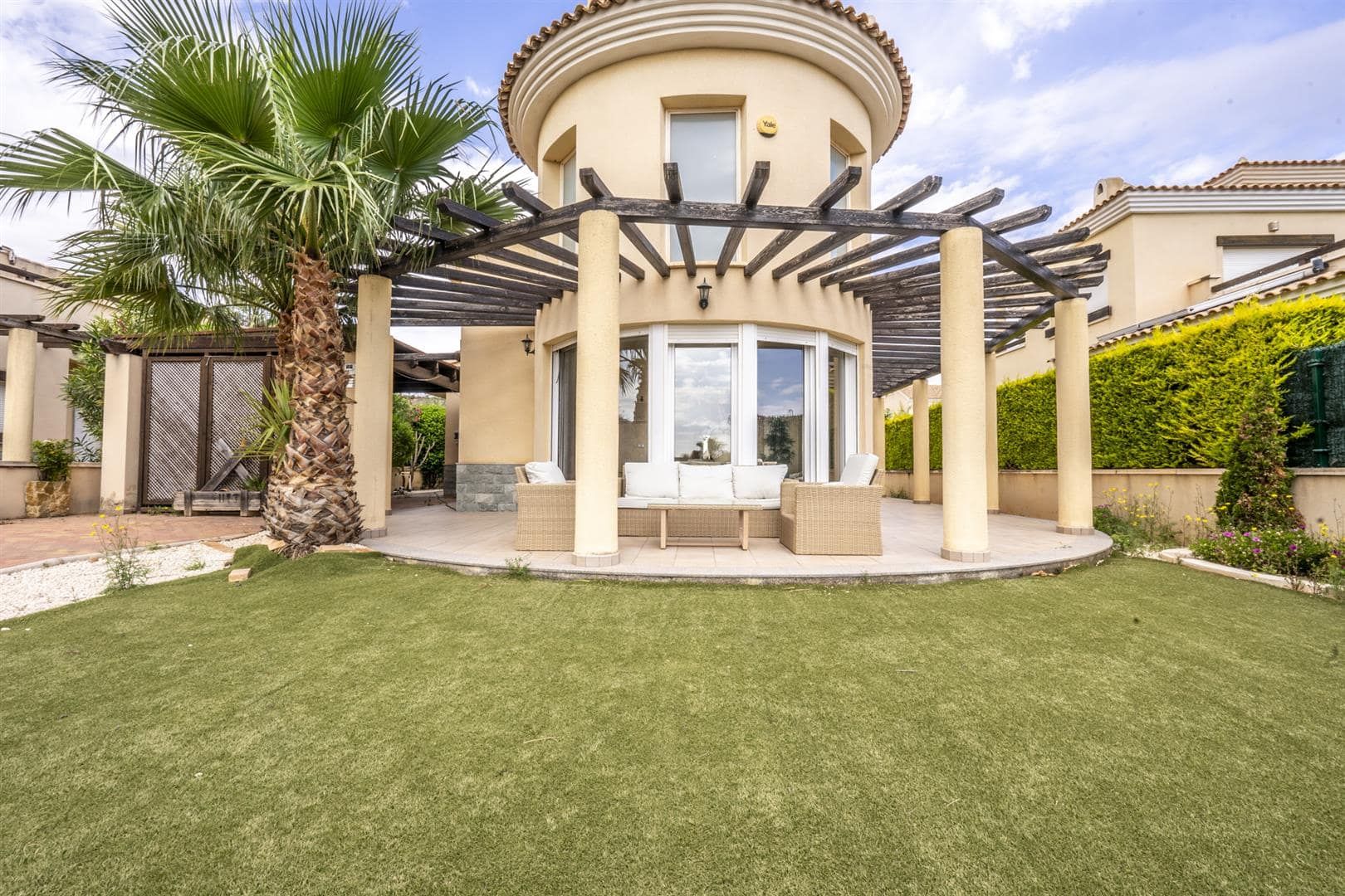 Rear garden view of the villa facade with rounded bay and pergola