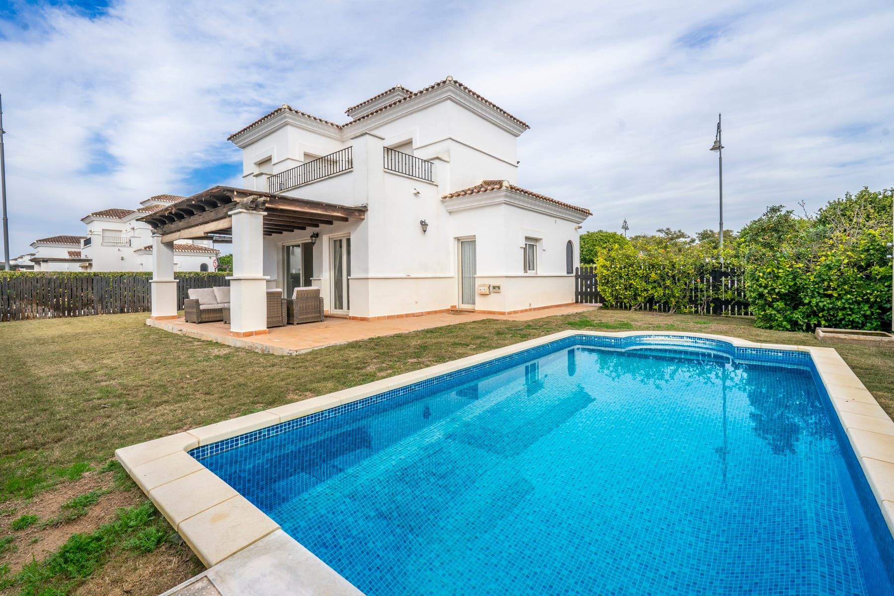 Swimming pool in front of the rear exterior and covered terrace of a white two-storey home