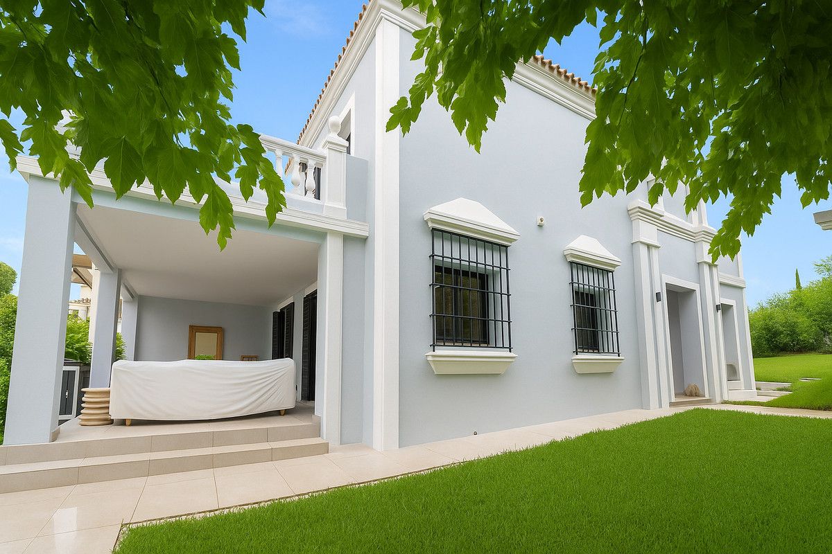 Garden elevation of the villa with a covered porch, balustraded upper terrace and wrought-iron window grilles framed by overhanging branches