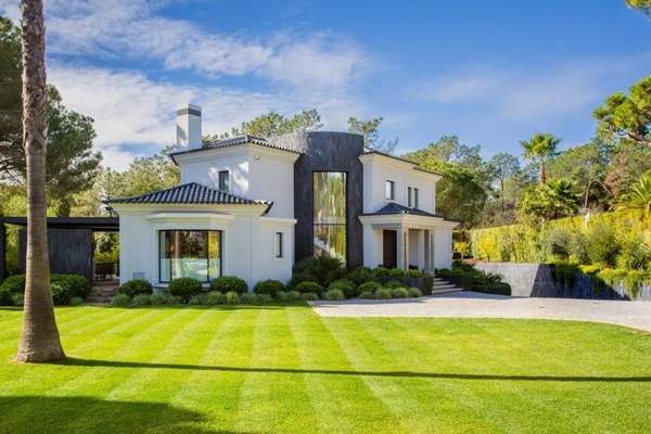Villa Golfe Norte framed by a lawn, pine trees and landscaped gardens