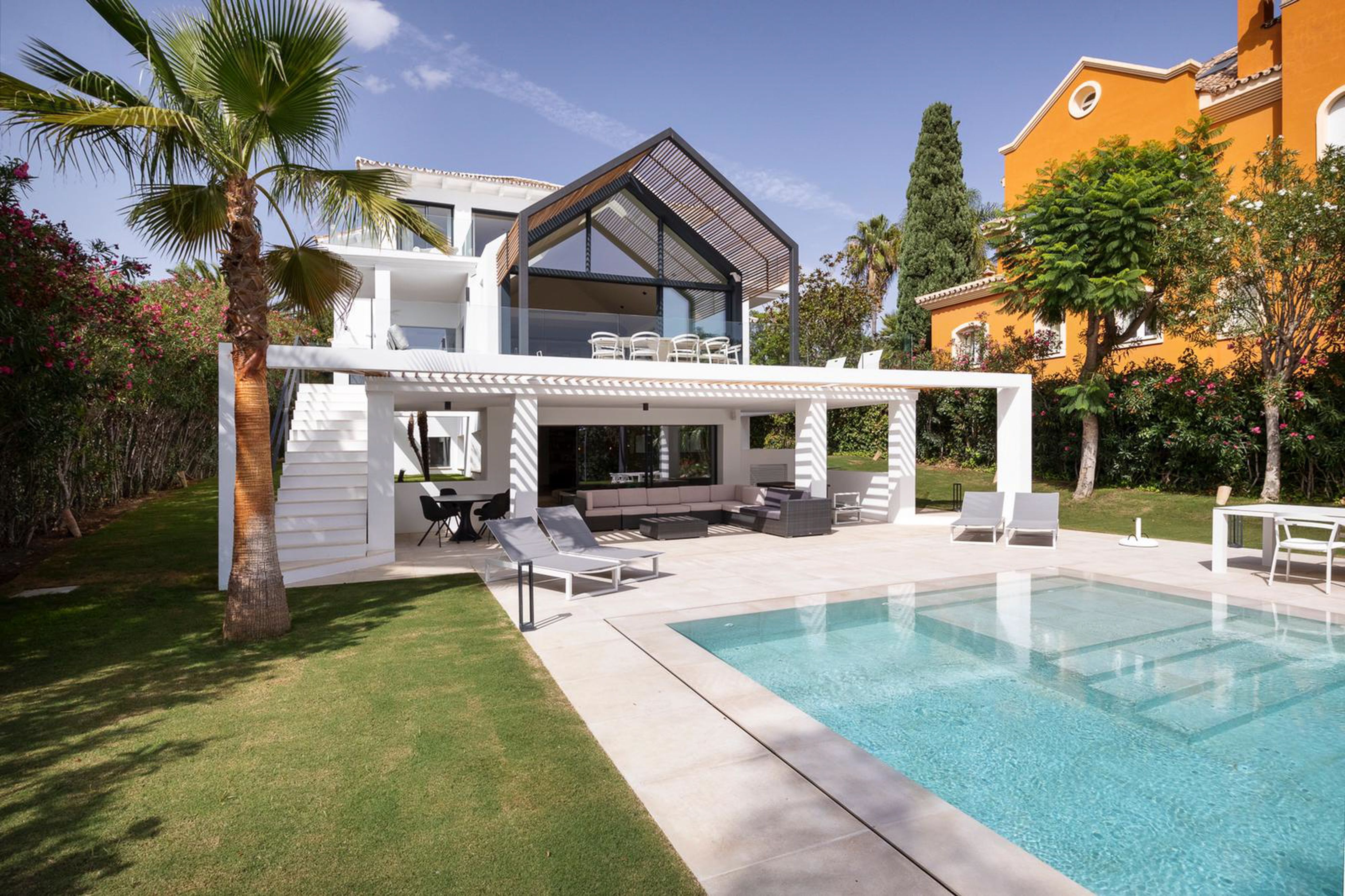 Pool and garden at La Madrugada with the villa's modern rear elevation and covered outside living area.