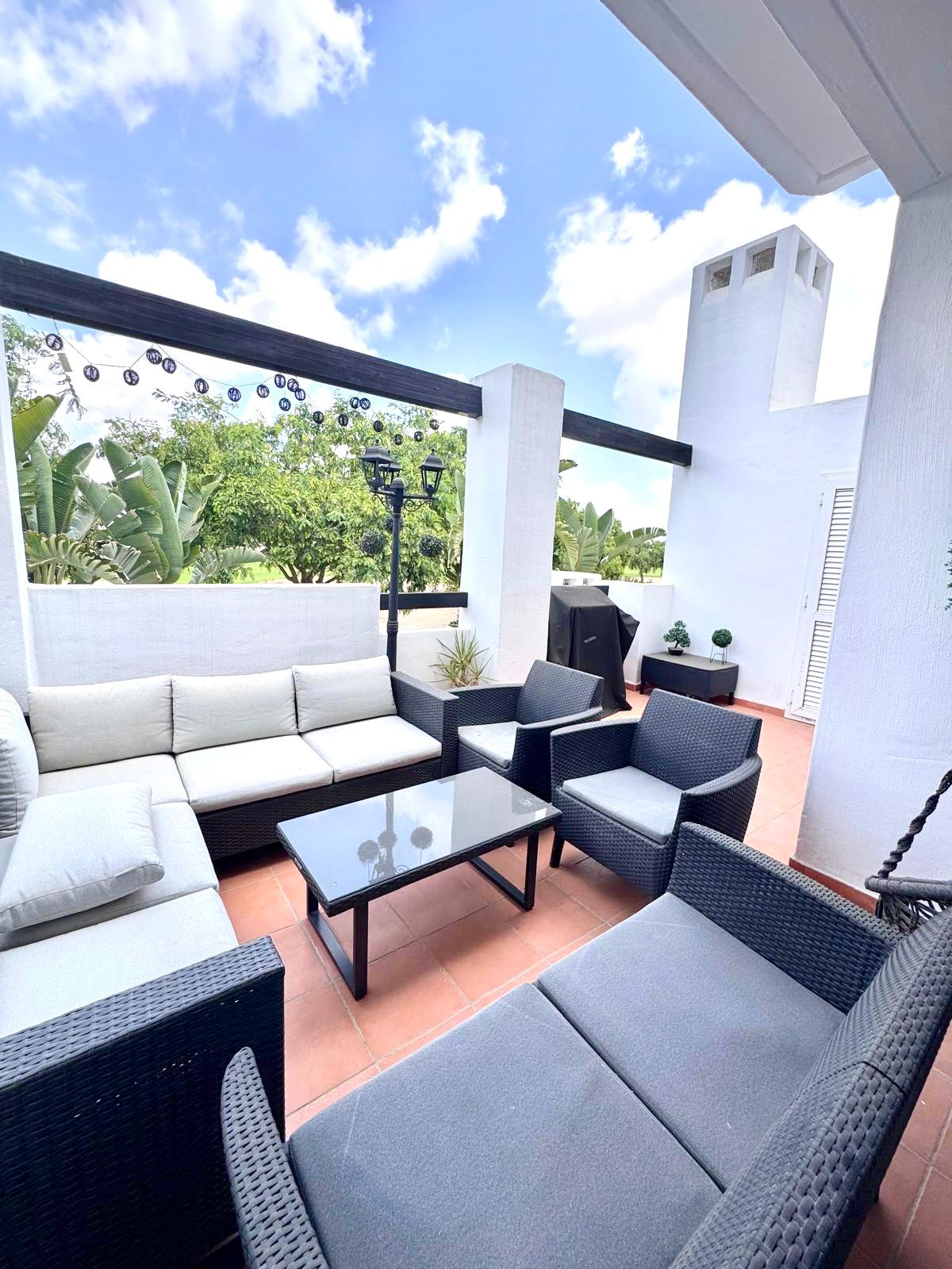 Furnished tiled terrace with white walls and outlook towards planting