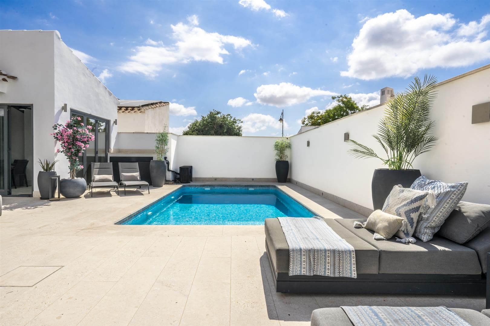 Private courtyard swimming pool with sun loungers and outdoor seating.