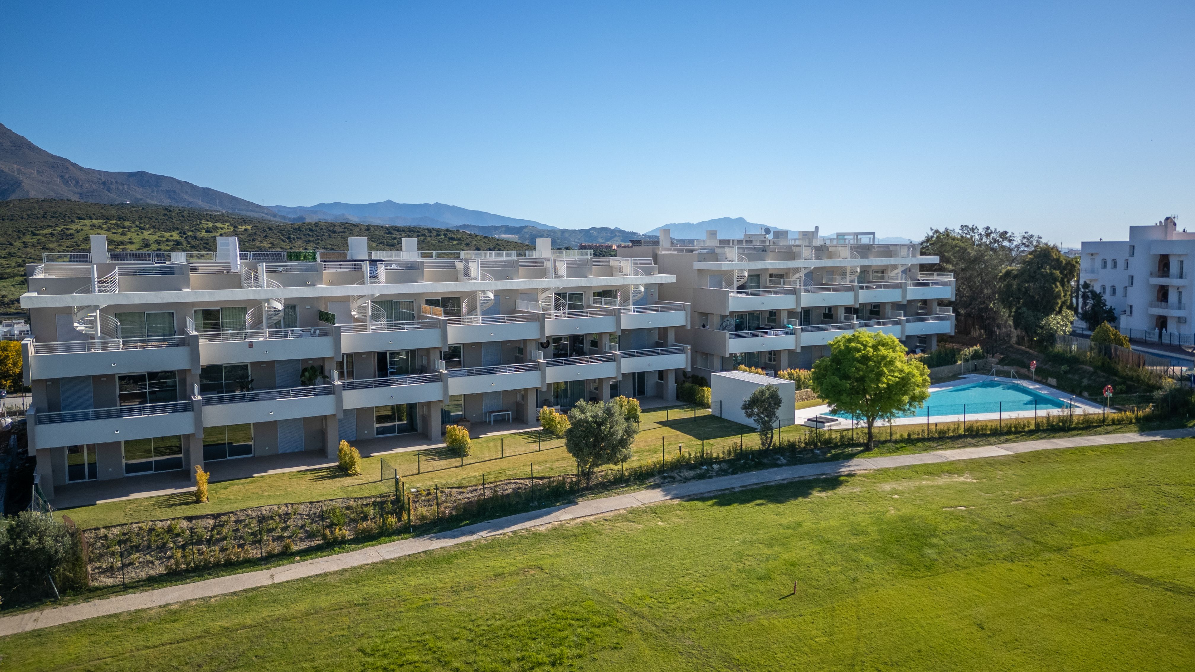 Completed Sunny Golf apartment buildings, communal pool and fairway in Estepona