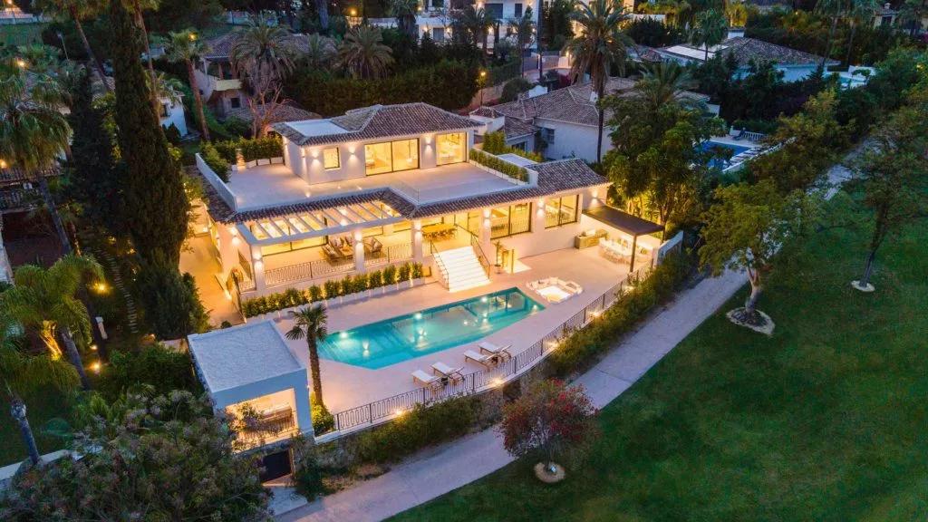 Villa Margarita illuminated at dusk beside its outdoor pool and golf course