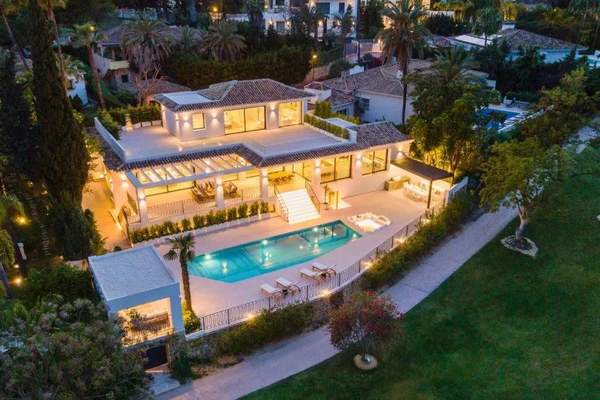 Villa Margarita illuminated at dusk beside its outdoor pool and golf course