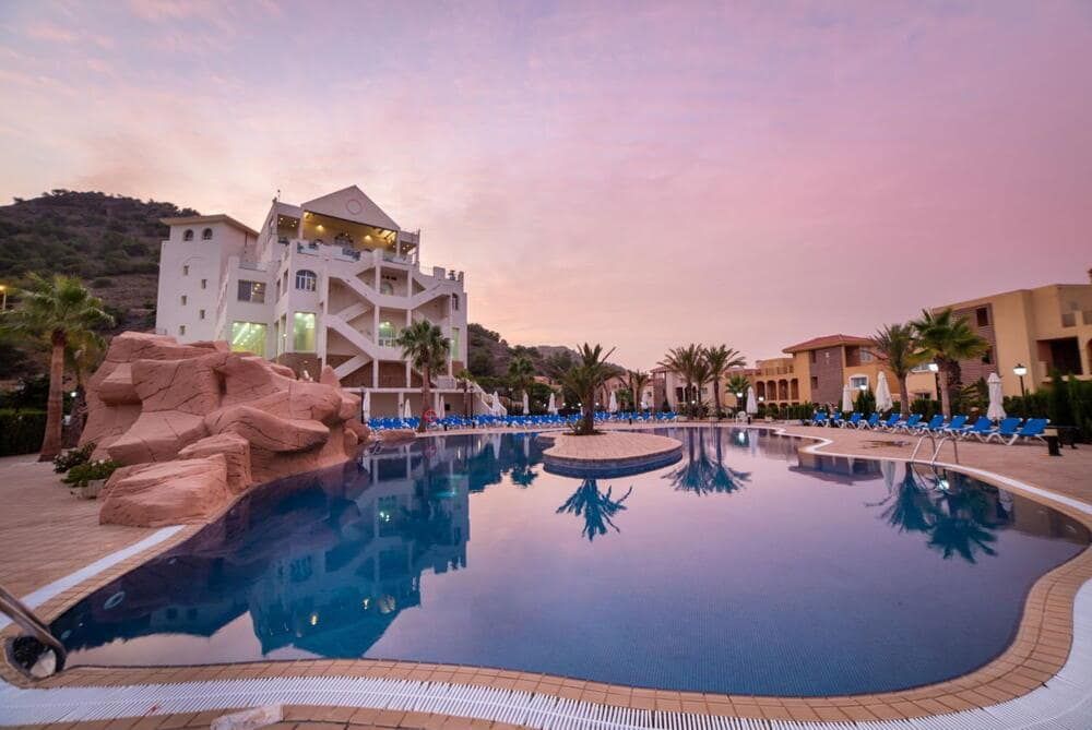 Large resort swimming pool and surrounding buildings at dusk.