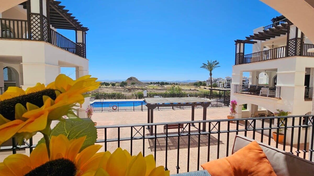 Terrace view across a swimming pool towards open landscape and distant hills.