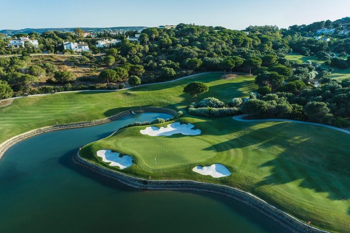 Golf green and lake with villas on the wooded hillside beyond, Sotogrande