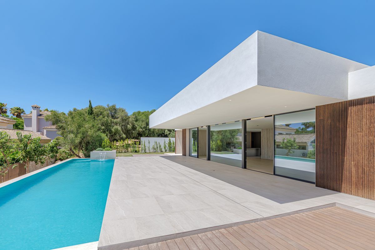Contemporary new-build villa in Sotogrande Alto with a long private swimming pool, wide stone terrace and a cantilevered white roof over full-height glazing