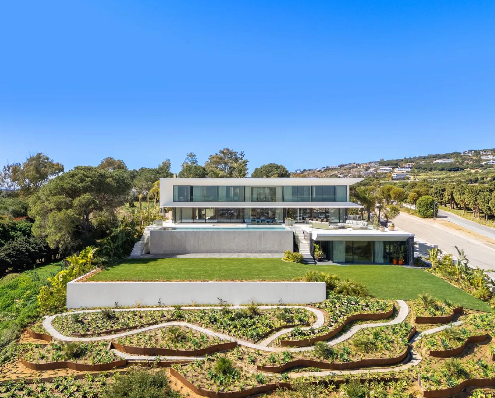 Elevated view of Villa Aldebaran with its glazed elevation, lawn and landscaped lower garden.