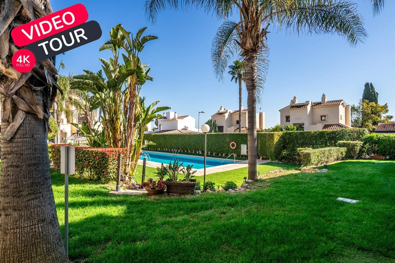 Landscaped communal garden and pool beside white townhouses