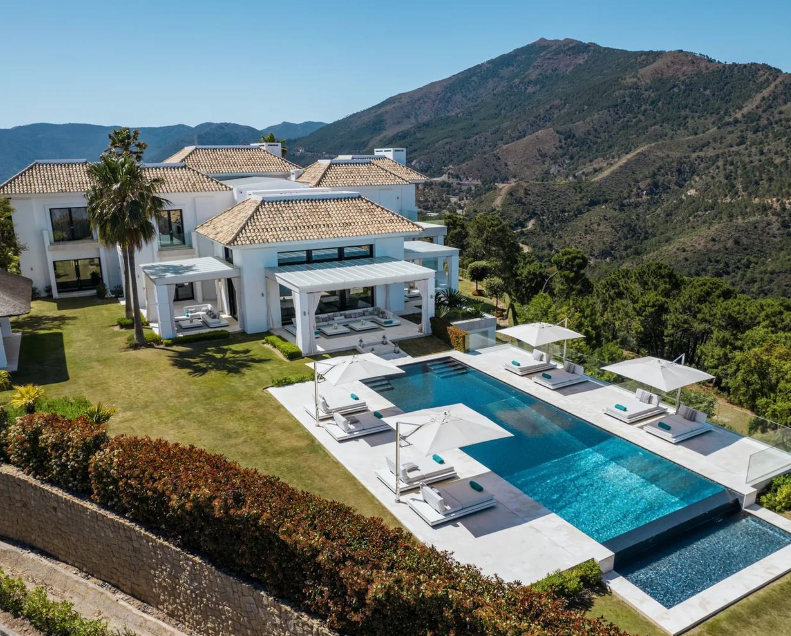 Aerial view of Casa Valentino, its garden and pool terrace against the La Zagaleta hills.