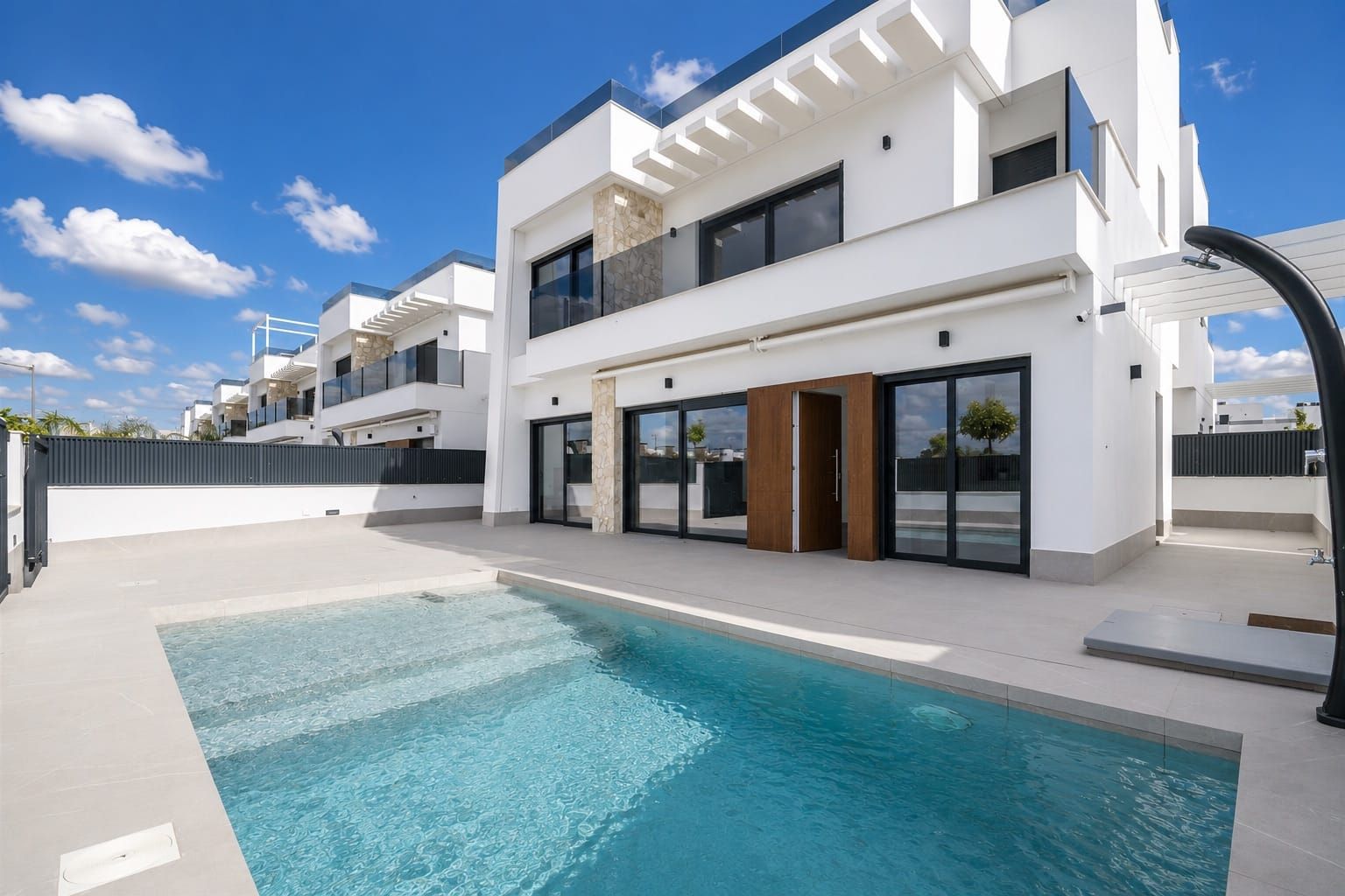 Modern white villa with a private swimming pool and paved terrace.