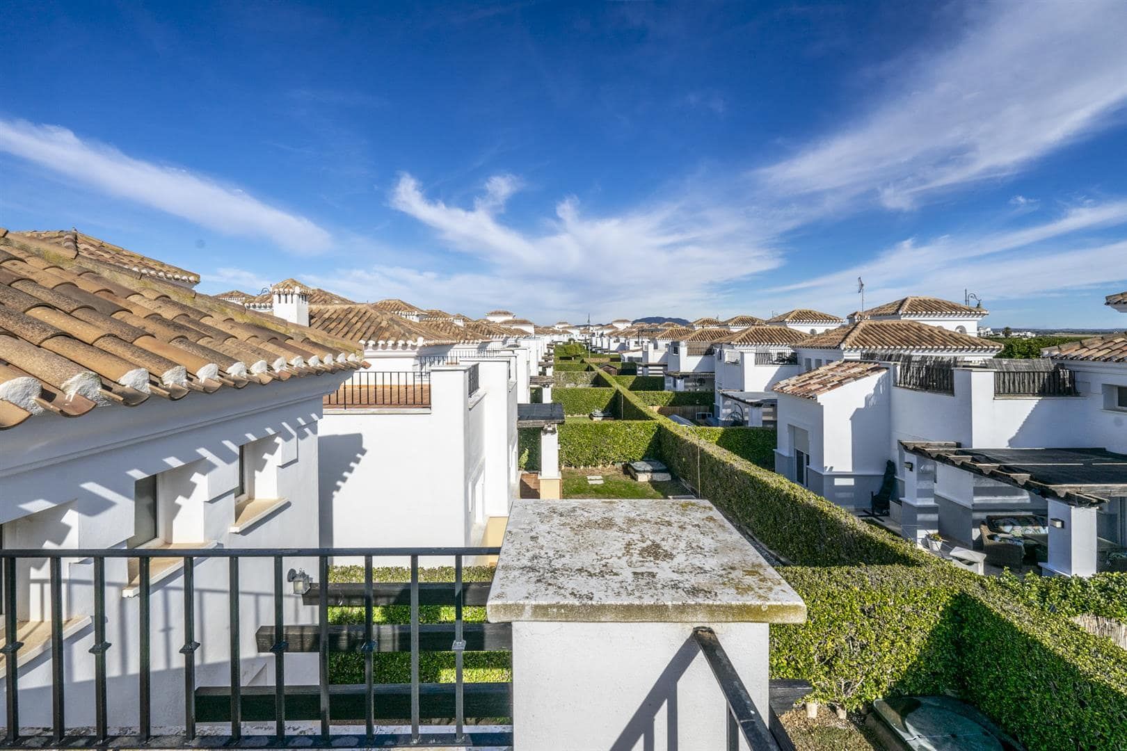 Elevated view across white resort villas, tiled roofs and clipped hedges.
