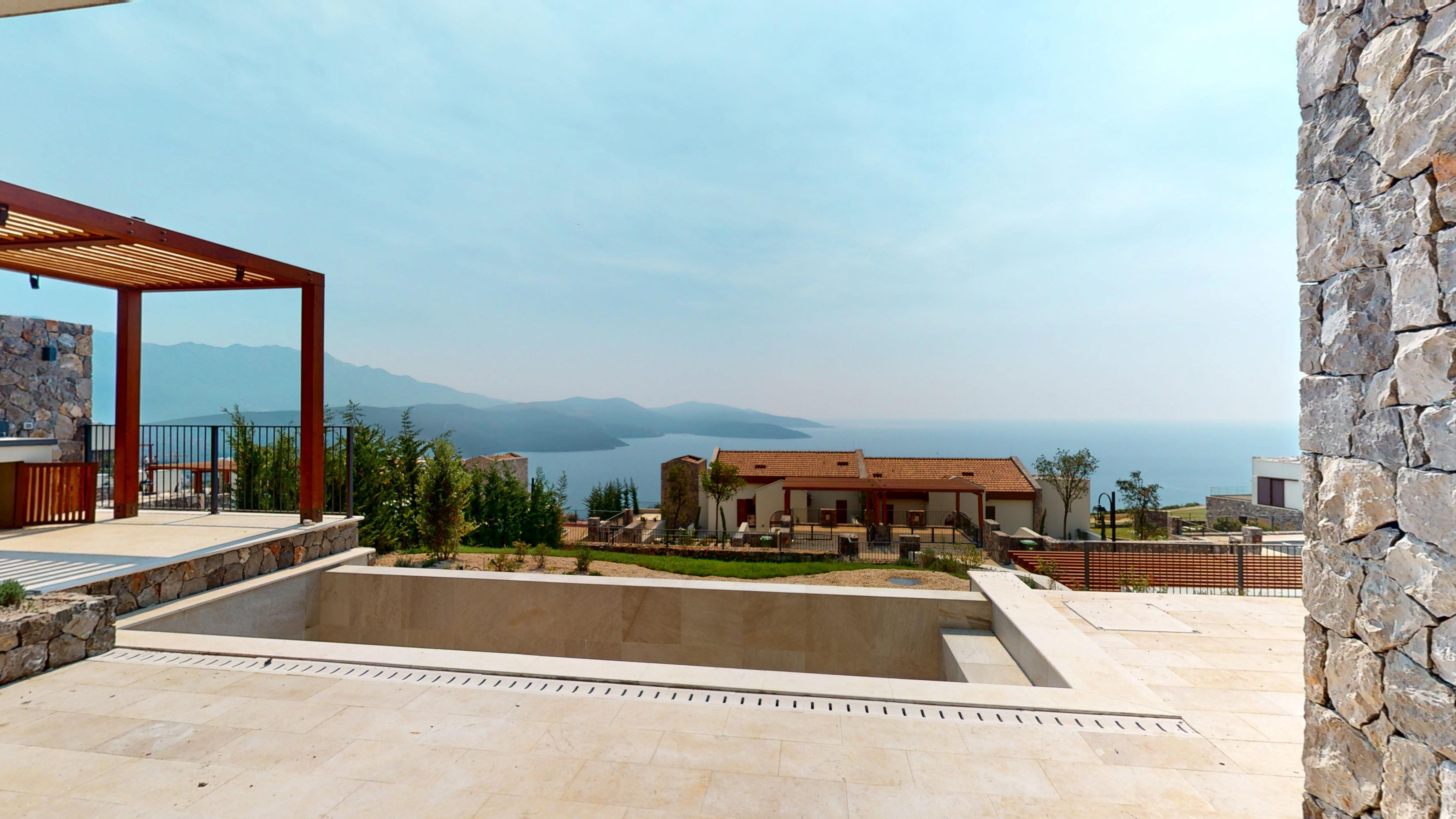 Stone terrace with a recessed outdoor feature and panoramic sea outlook at Townhouse GTH3A in Golf, Luštica Bay