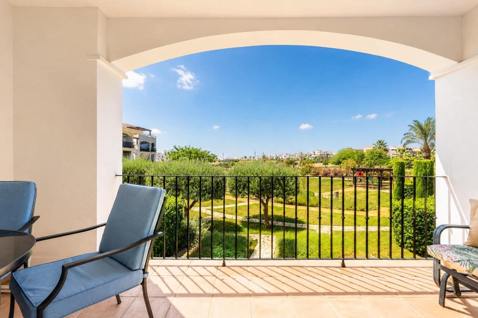 Covered terrace framed by an arch with seating and landscaped garden outlook.