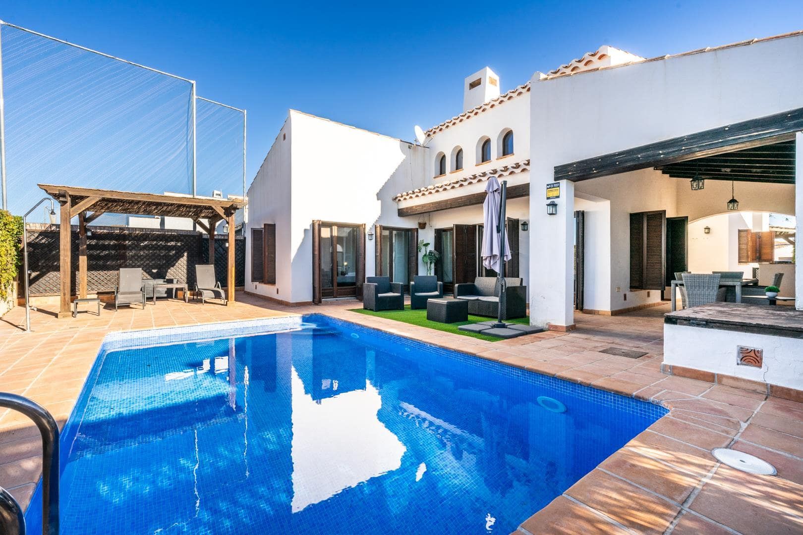 White villa with a private swimming pool, covered dining terrace and poolside seating.