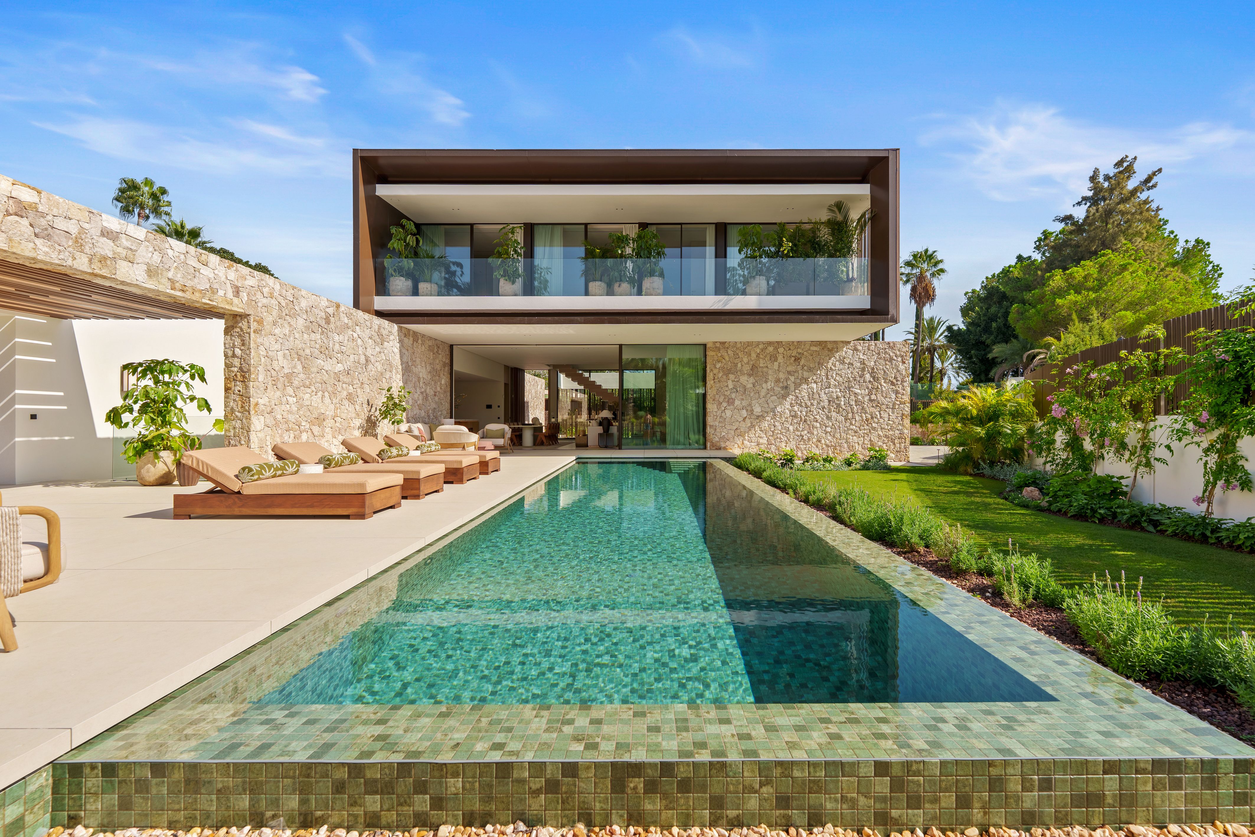 Casa Cazorla exterior with pool, garden and contemporary stone facade.