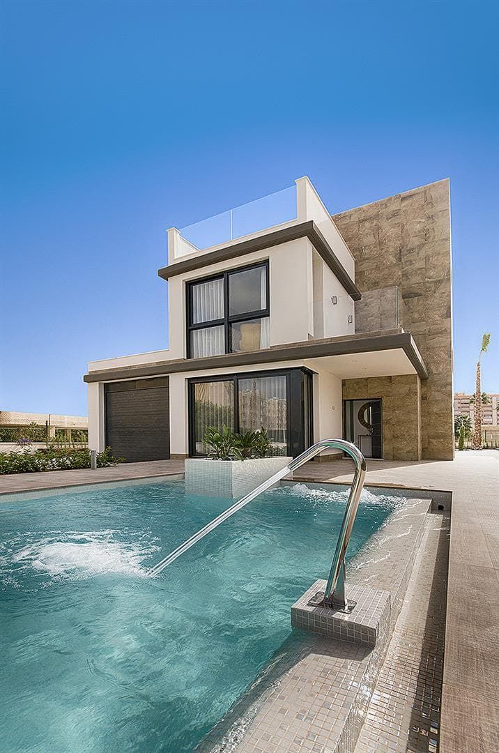 Photograph across a swimming pool towards a contemporary two-storey villa in daylight