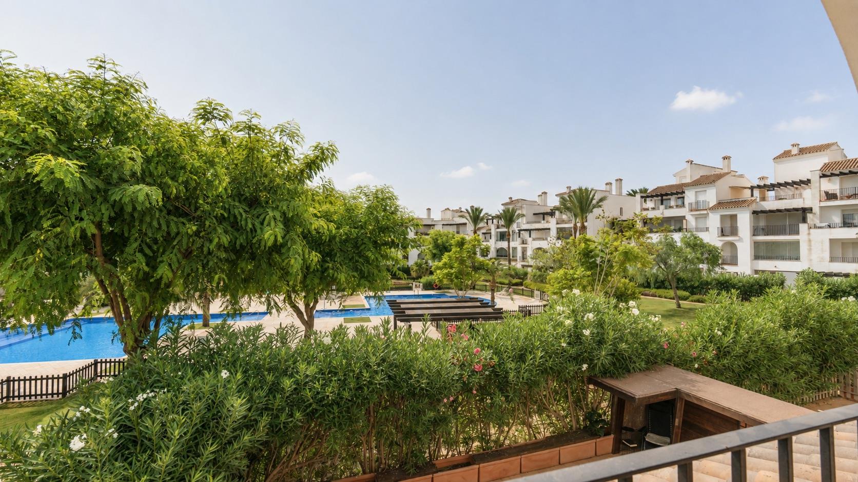 Terrace view across landscaped gardens towards a shared swimming pool.