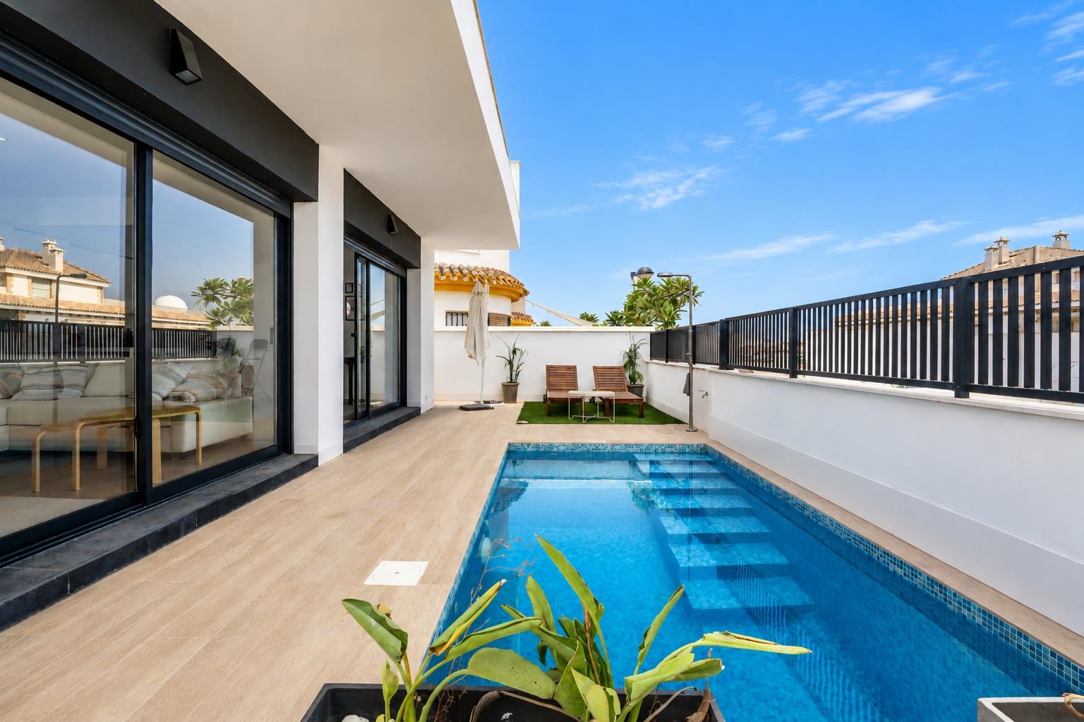Swimming pool running beside the modern white villa and glazed living space.