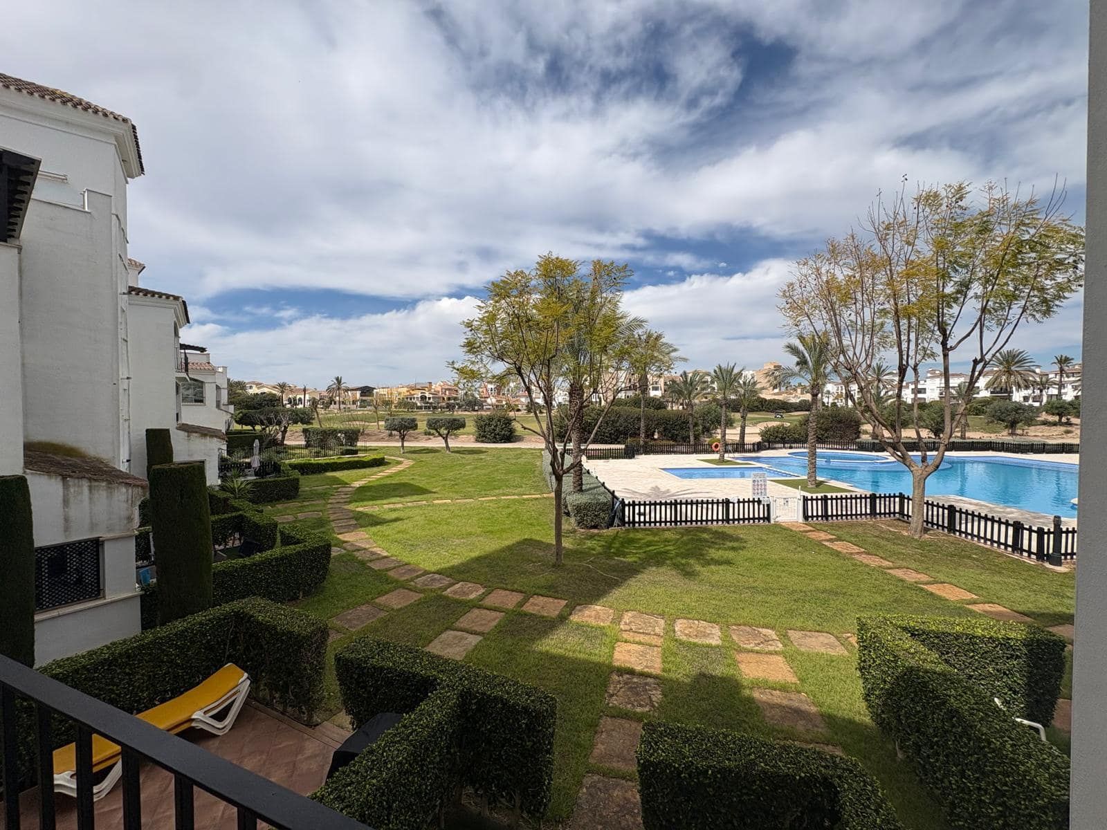 Open balcony outlook across landscaped grounds with a swimming pool visibly in view
