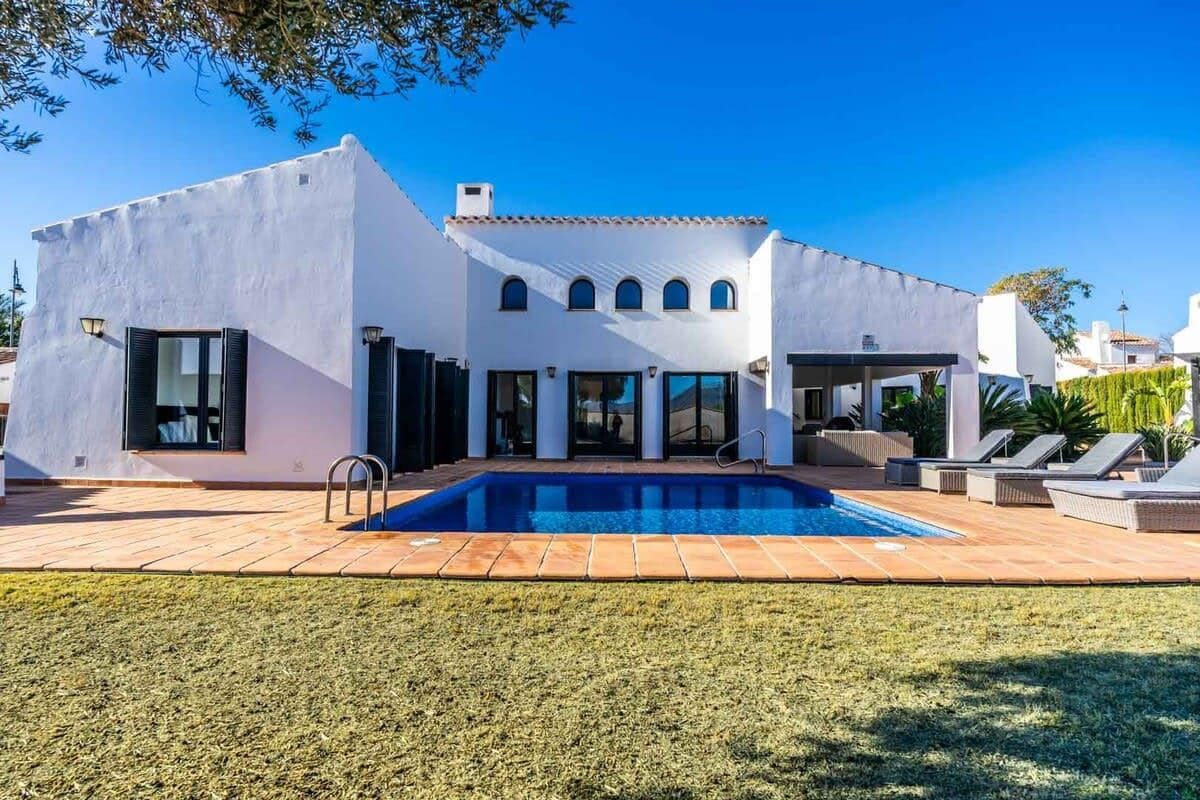 White villa with a swimming pool, terracotta terrace and lawn.