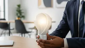 A creative professional at a wooden desk holding a stylized lightbulb icon, signifying a new invention or creative work in a modern office.