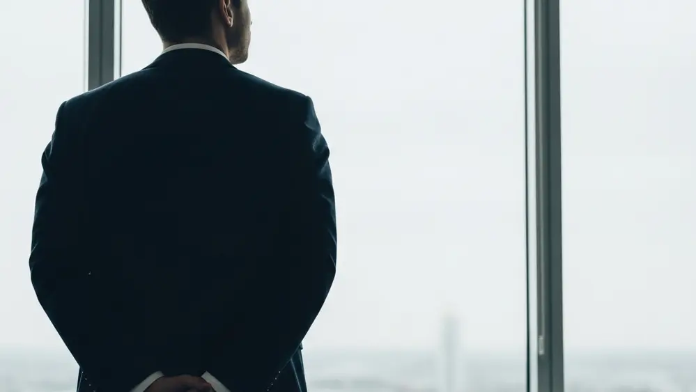 A somber, contemplative image showing a person looking out a window, representing reflection and the search for justice and healing.