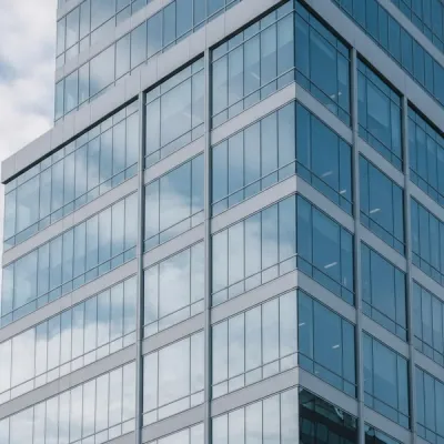 A modern corporate office building with glass windows reflecting the sky, representing an environment under federal investigation.