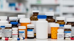 An array of various prescription medication bottles on a clean, reflective pharmacy counter, representing the wide range of drugs in modern medicine.