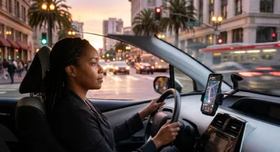A rideshare driver sits in a modern vehicle on a busy California city street at sunset, looking at a smartphone mounted on the dashboard.