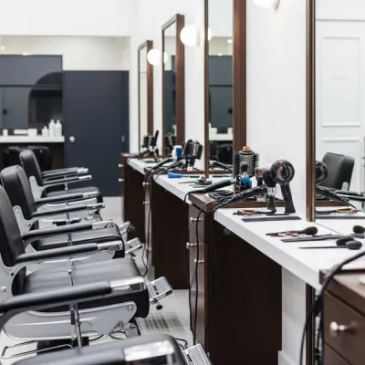 A modern hair salon interior with empty barber chairs and styling tools on a counter reflecting a professional workplace environment.