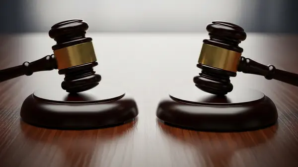 A symbolic image of two gavels resting on a dark wooden surface, representing the separate but parallel systems of civil and criminal law.