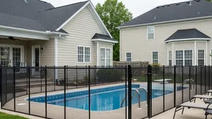 A suburban backyard featuring a swimming pool enclosed by a sturdy black metal safety fence with a child-resistant gate.