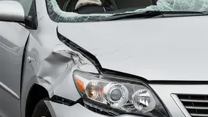 A silver Toyota sedan with significant front-end damage from a crash where the interior steering wheel is visible but the airbag has not deployed.