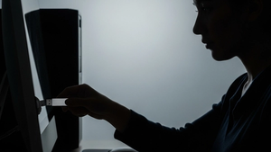 A silhouette of a person in a dark office using a USB drive on a computer workstation, symbolizing a digital data breach.