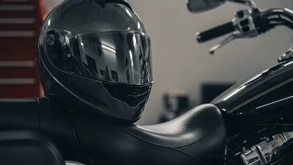 A modern motorcycle helmet resting on the seat of a parked cruiser motorcycle in a garage.