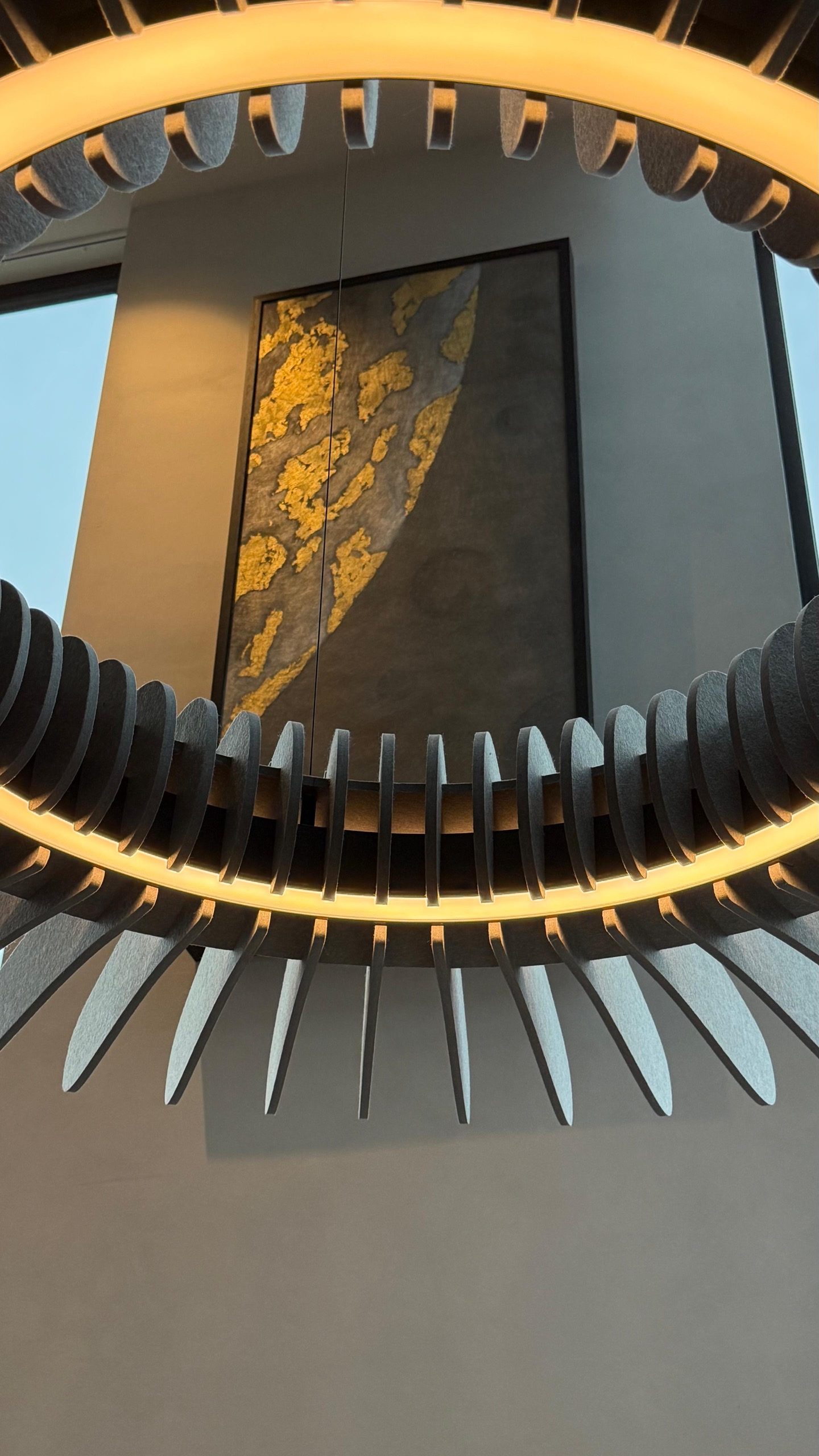 The tall work seen from below, past a circular pendant of standing blades.