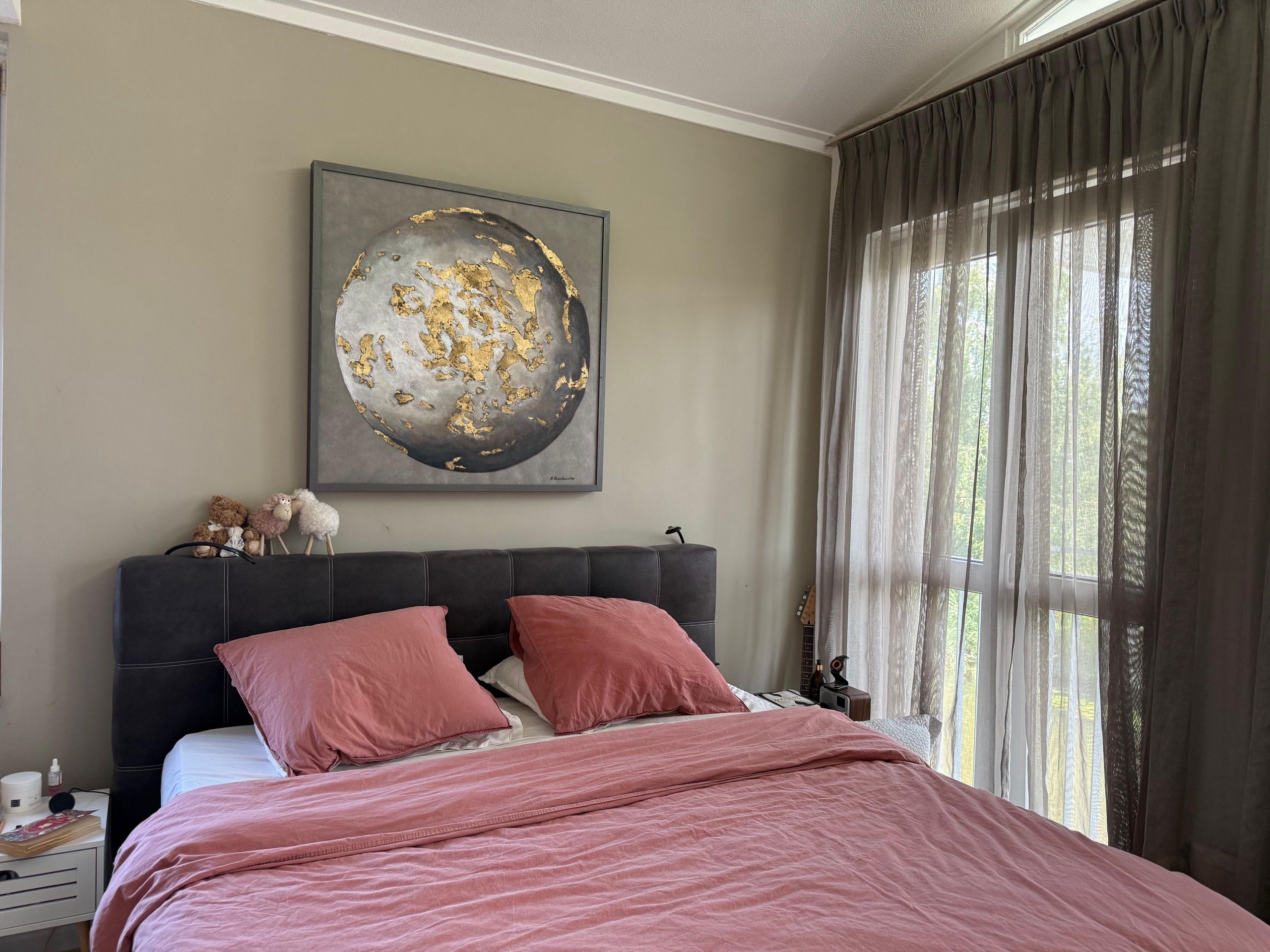A grey and gold moon above a bed.