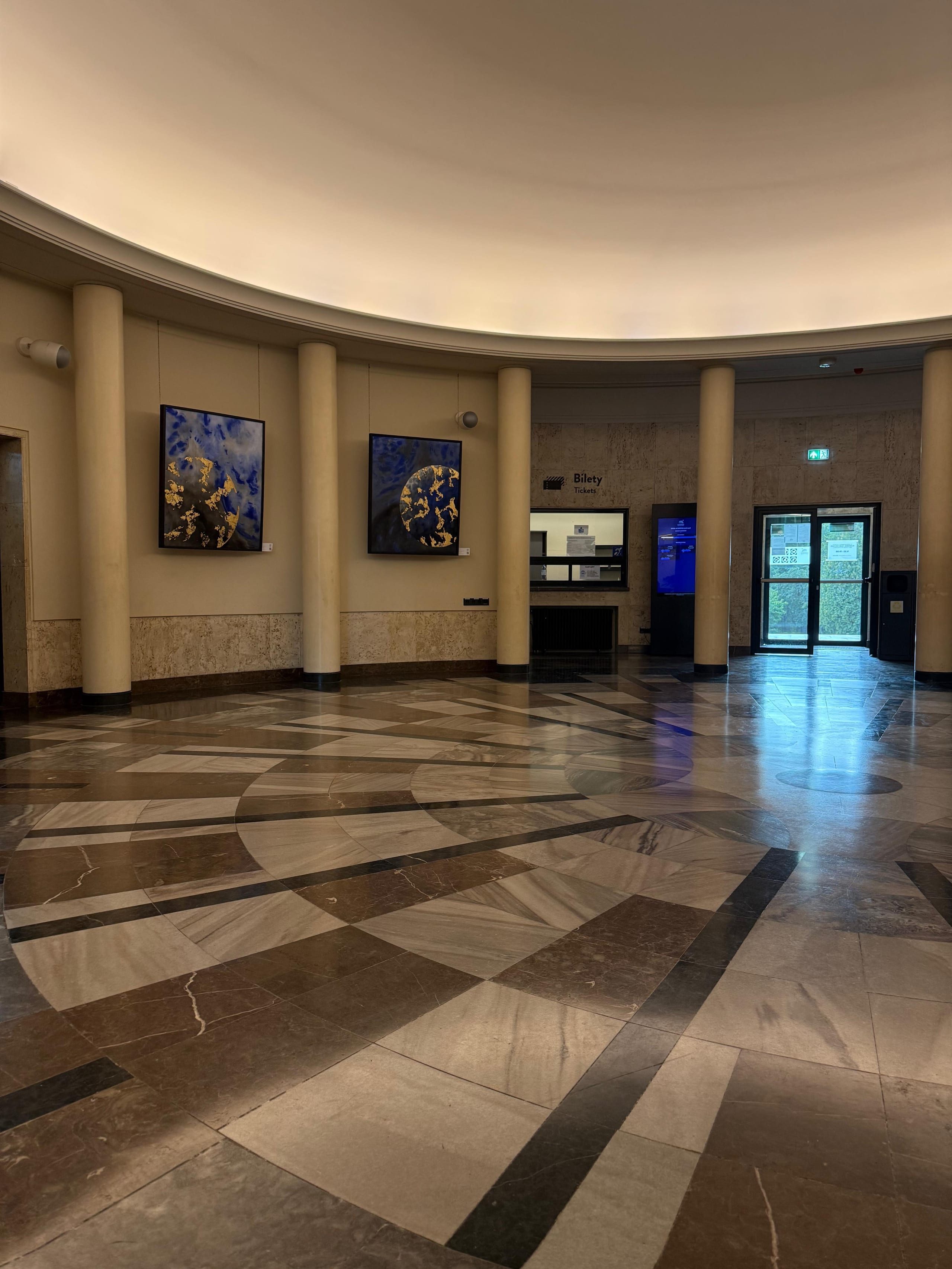 Two blue and gold planetary paintings in the round marble foyer of the planetarium.