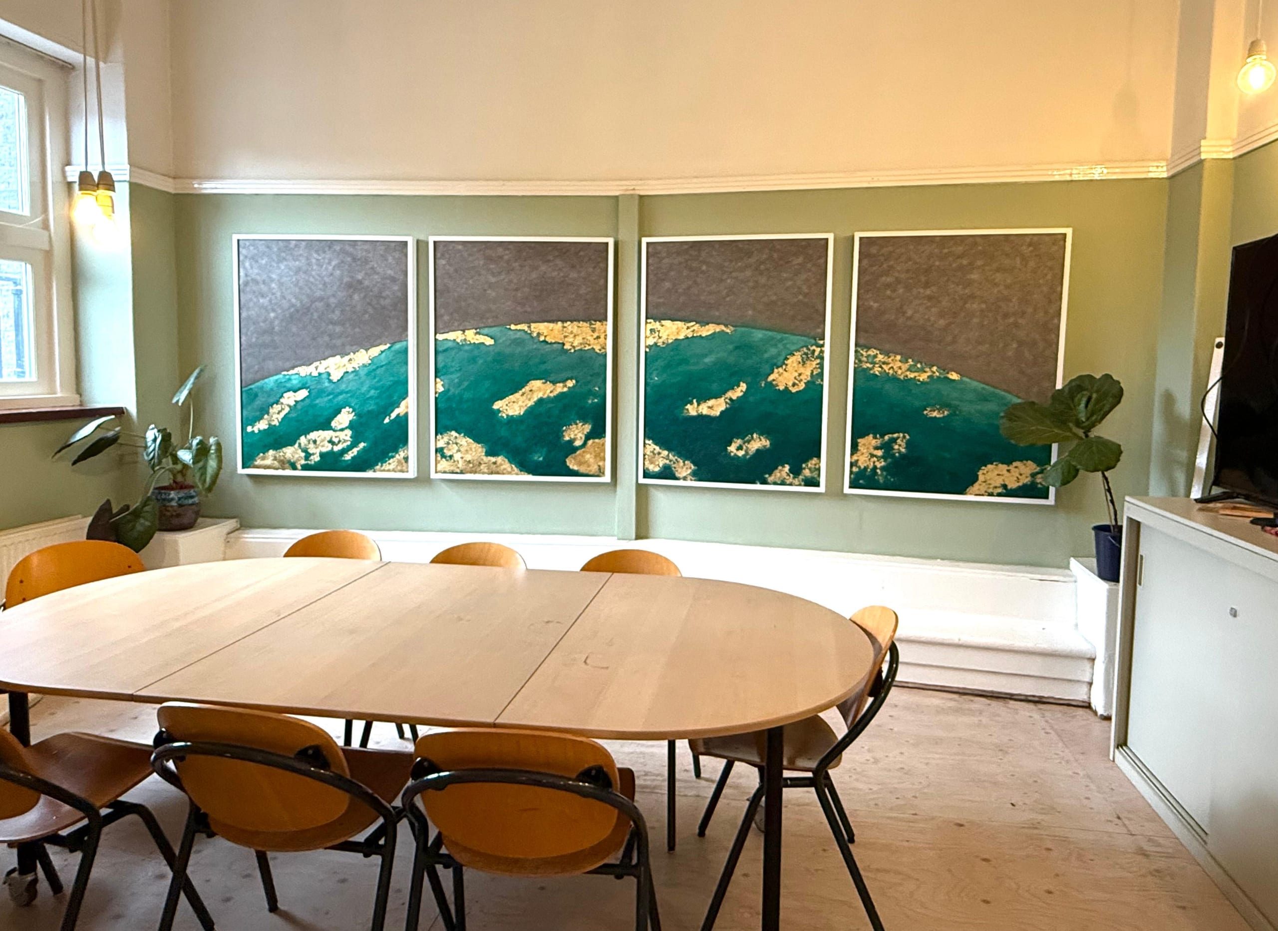 A four-panel work in emerald and gold above an oval meeting table.