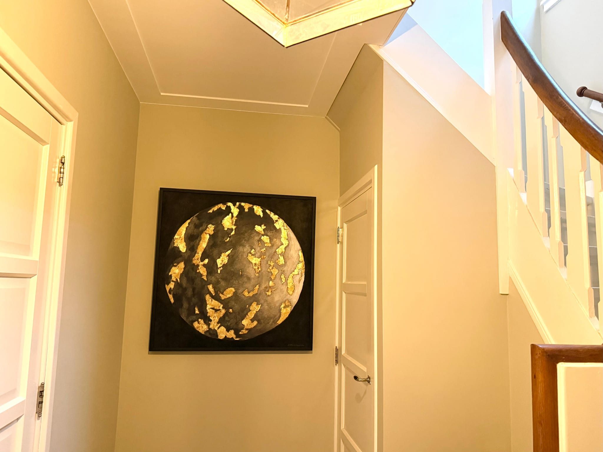The same hallway seen from the stairs, the work between two white doors with daylight from above.