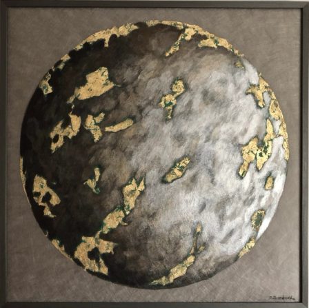 A planet turning from black to white, its continents in gold-coloured metal leaf, in a grey frame.