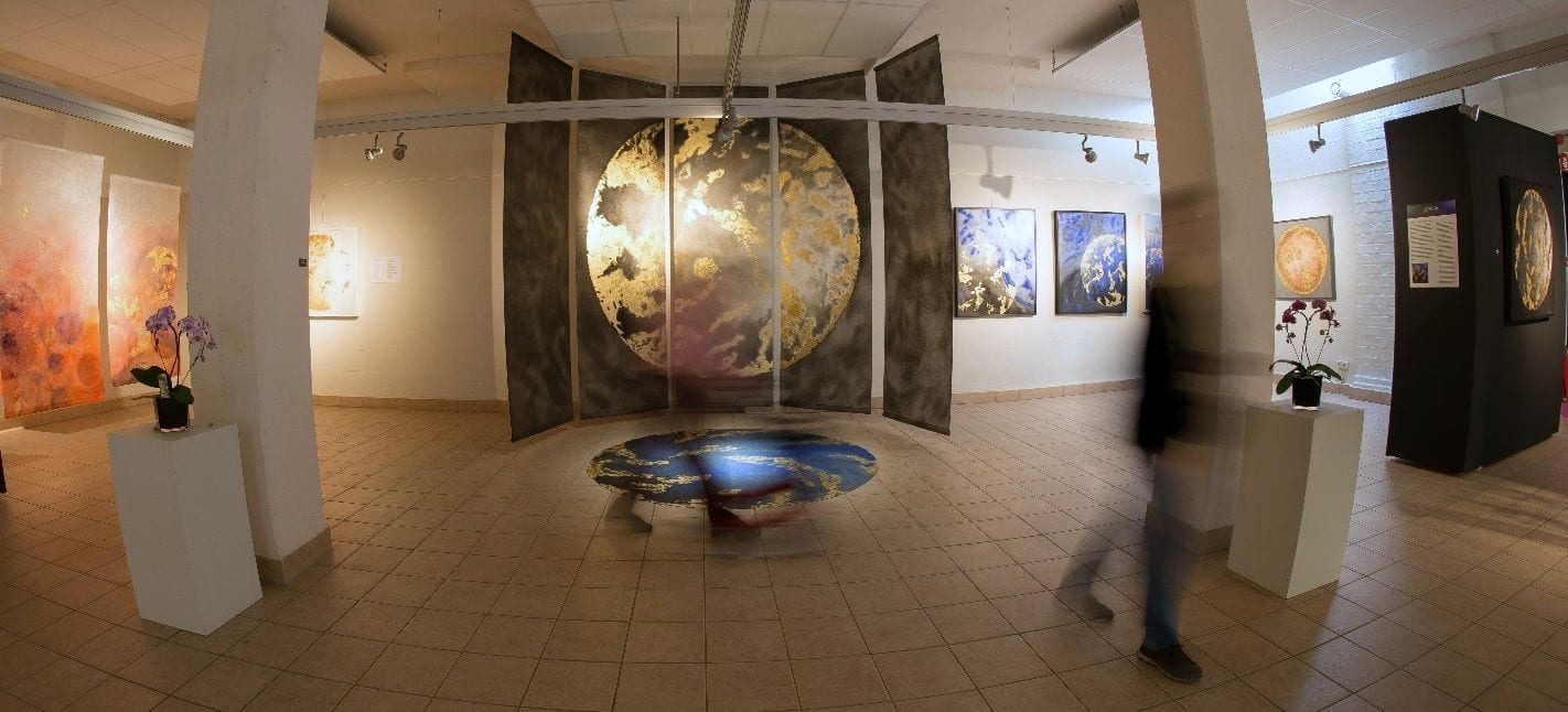 The hall of the Flower Art Museum: a large golden planet on painted panels in the centre, with a round disc on the floor beneath it.